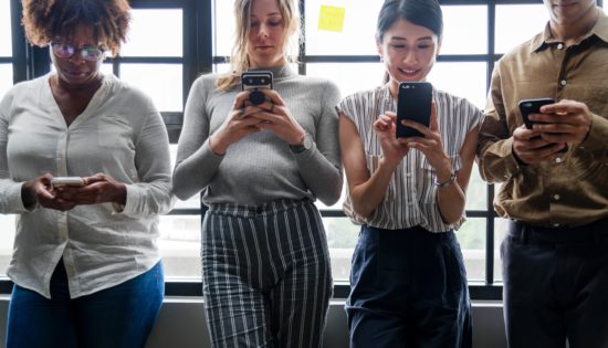 Four humans looking down at their mobile devices