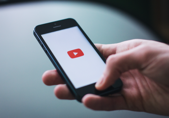 hand holing iPhone with youtube logo 