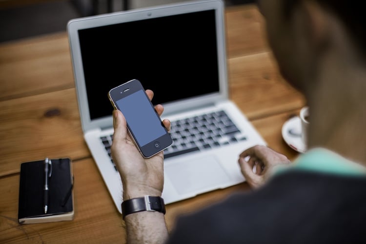 Person using their smartphone and laptop