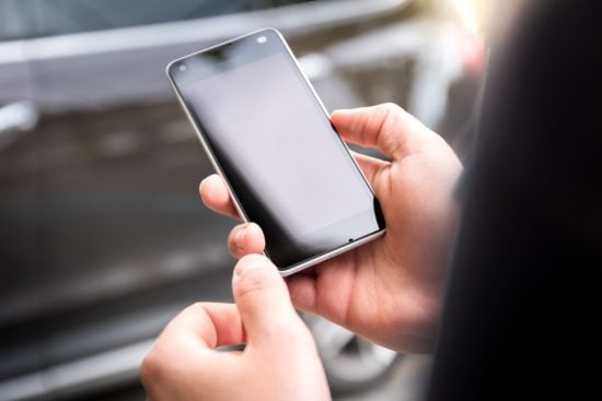 human looking down at a phone that he is holding with both hands