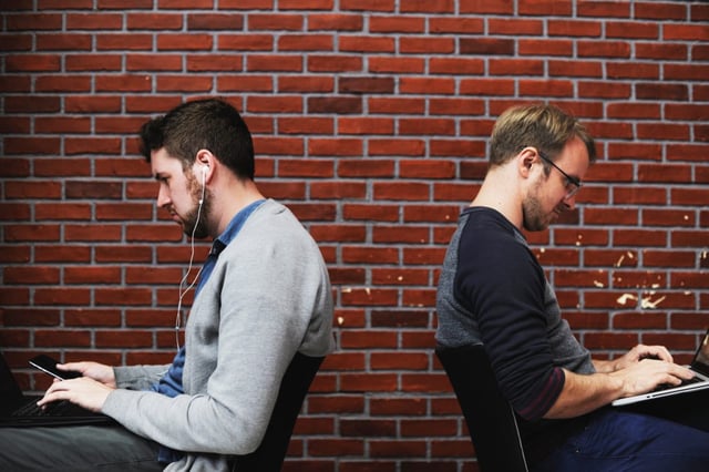 two men facing back-to-back on technology