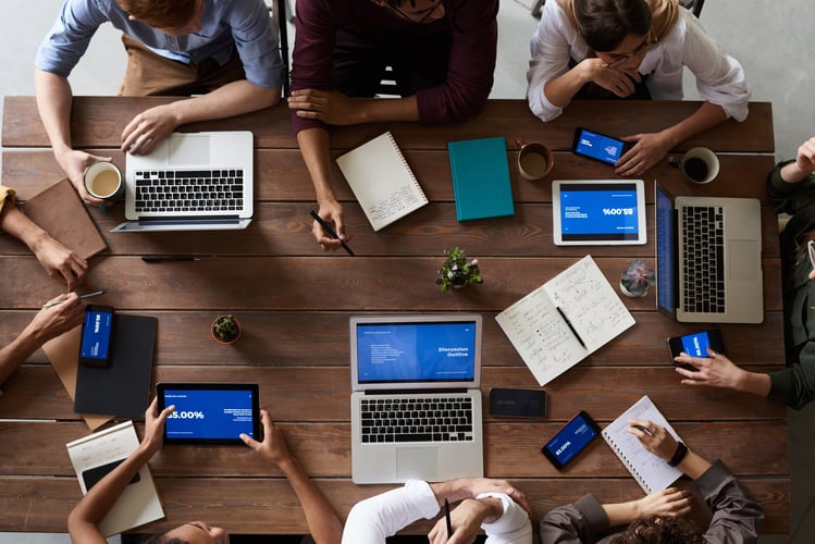 Top view photo of people working in collaboration on a wooden table