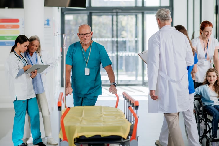 caregiver-pushing-hospital-bed-at-corridor-his-co-2023-11-27-05-09-36-utc
