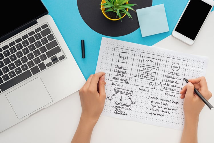 UX Designer sketching mobile app wireframes at a workspace