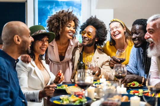 A group of friends, with difference user personas, laughing and enjoying a meal together