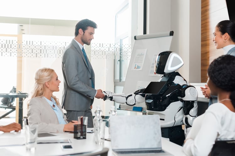 Background image of handsome businessman shaking hands with robot near multicultural colleagues sitting in conference
