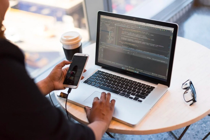 person-looking-at-phone-and-at-macbook-pro-1181244-716x477