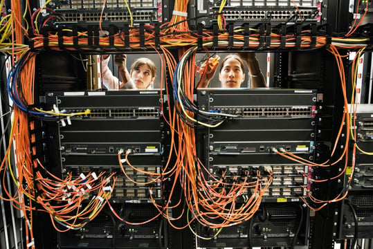 Background image of technicians working on a CAT 5 cable bundling system in a server room