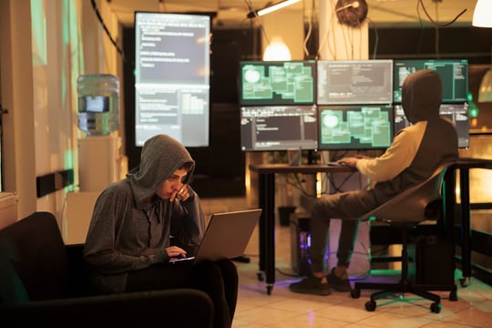 Background image of Two hackers working on computers to crack encryption