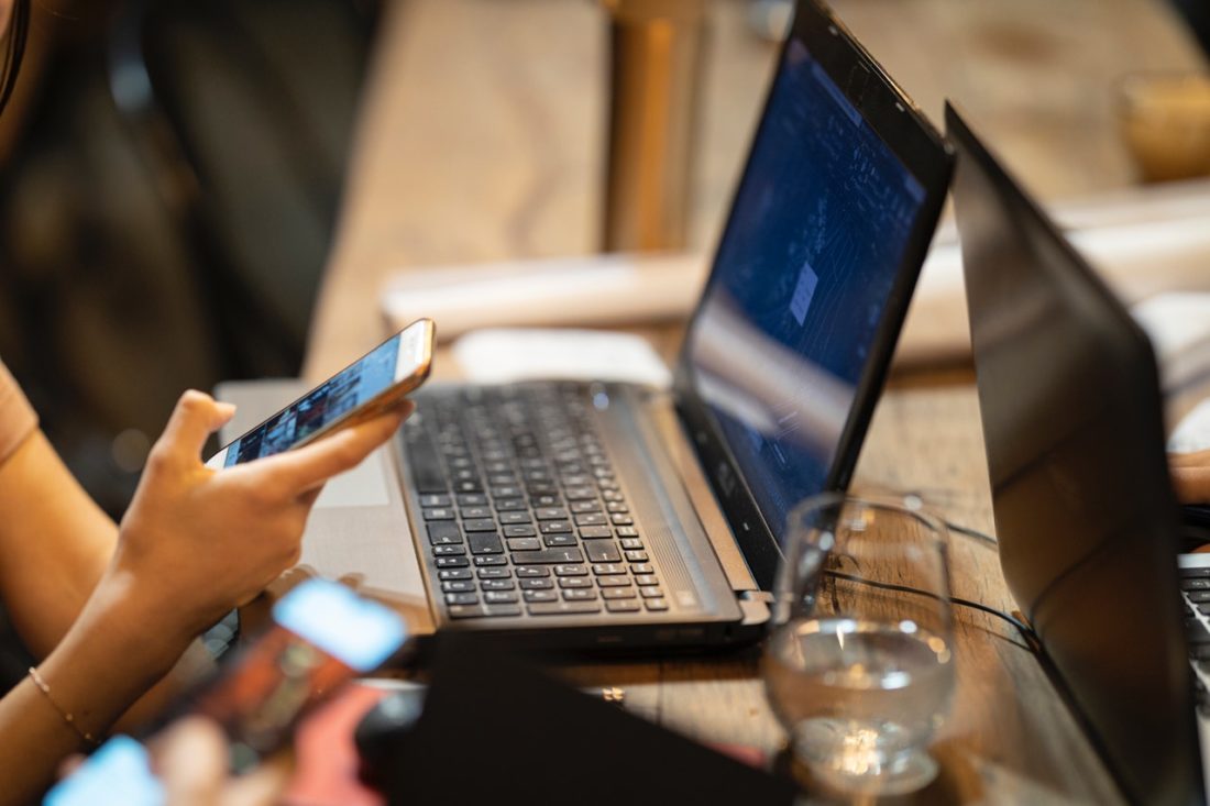 person using mobile phone and computer