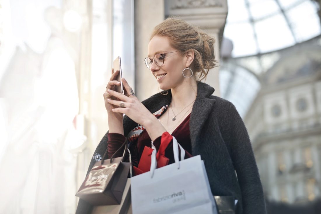 woman holding shopping bags and phone