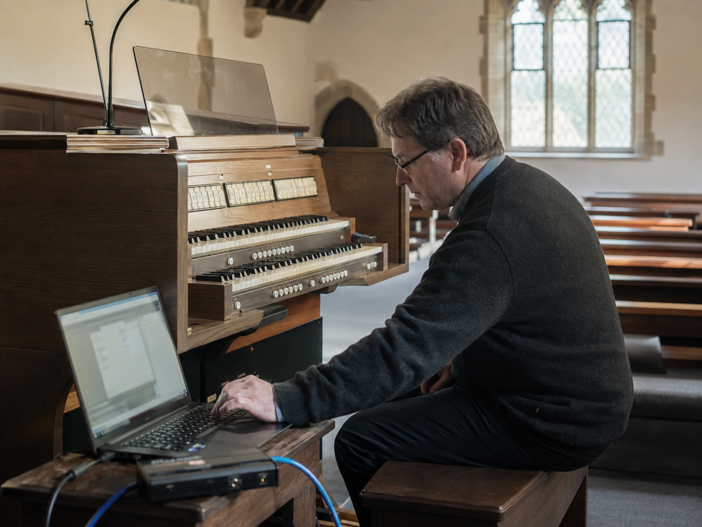 Specialist using a laptop alongside an organ console during an on-site validation setup.